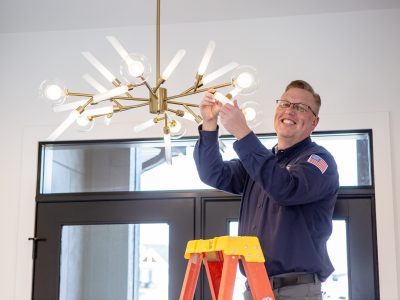 Lighting Services Iowa - Electrician in Blue Shirt Repairs Light