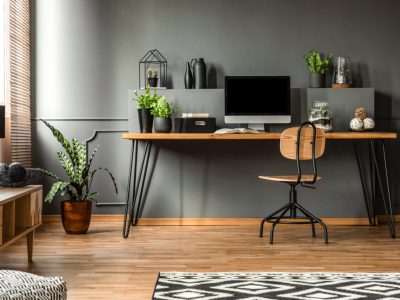 Real photo of a dark interior with wooden desk, chair and computer in the study space in the middle