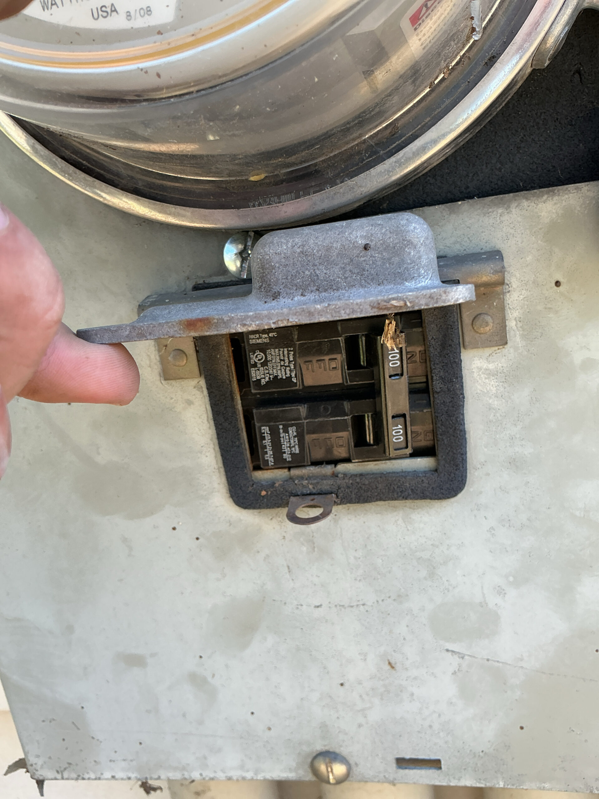 New Siemens 100-amp two-pole main breaker installed in the meter-main enclosure under the meter, with the weather cover lifted